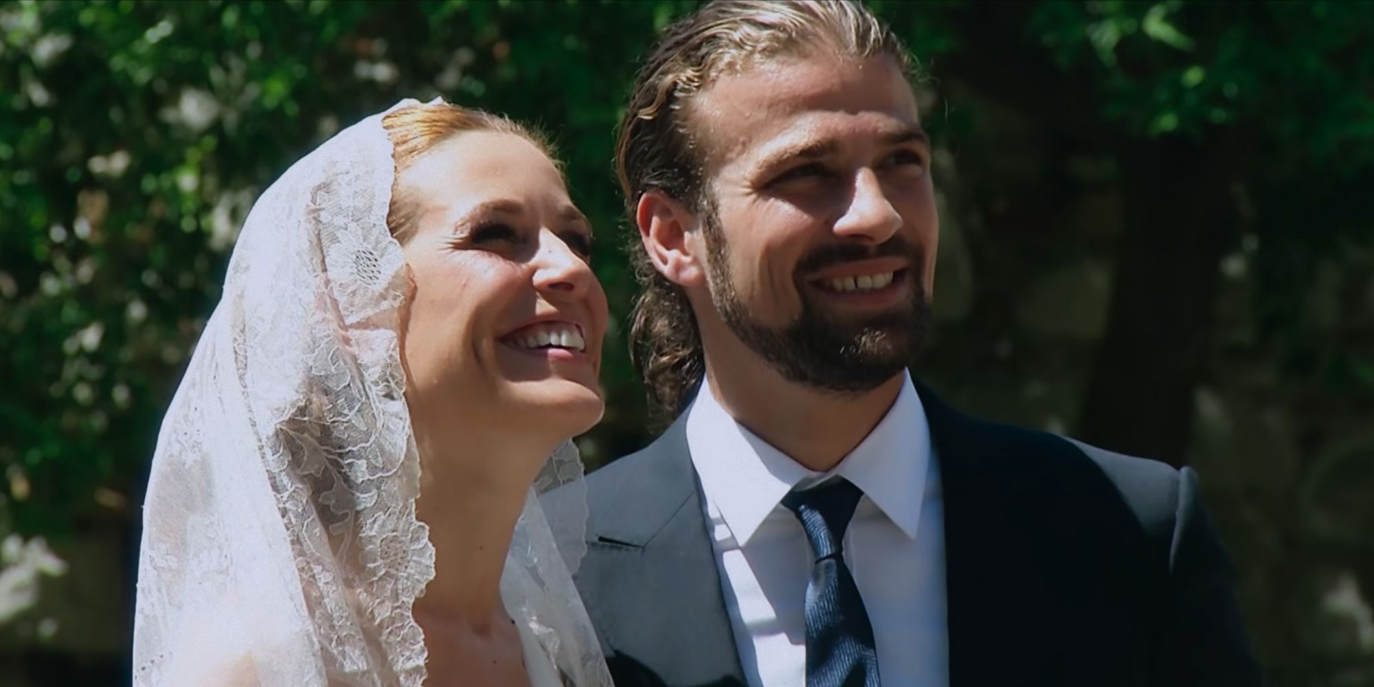Raquel Sanchez Silva in a bridal veil and Mario Biondo in a suit and tie, both smiling and looking to the right