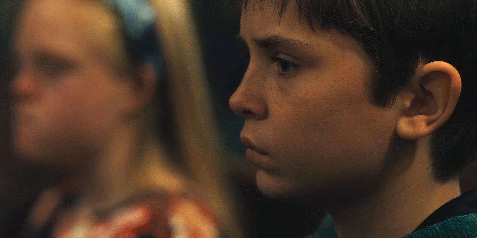 Ryan staring straight forward looking serious, with his sister Moira sitting next to him in the background