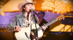 American Idol's John Foster performs on stage with a guitar