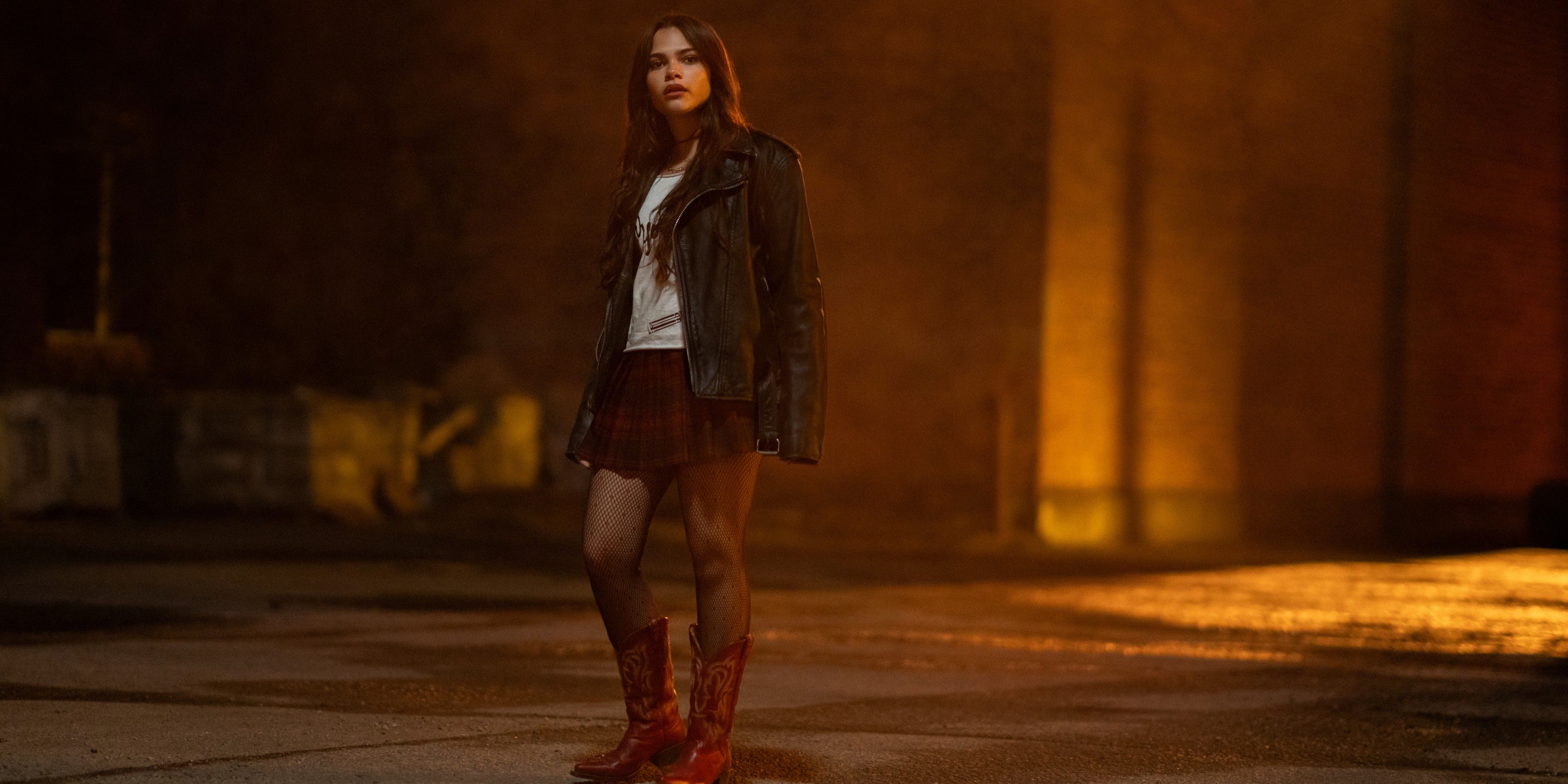 Christy wears red cowboy boots, a red plaid skirt, and a leather jacket in Fear Street: Prom Queen