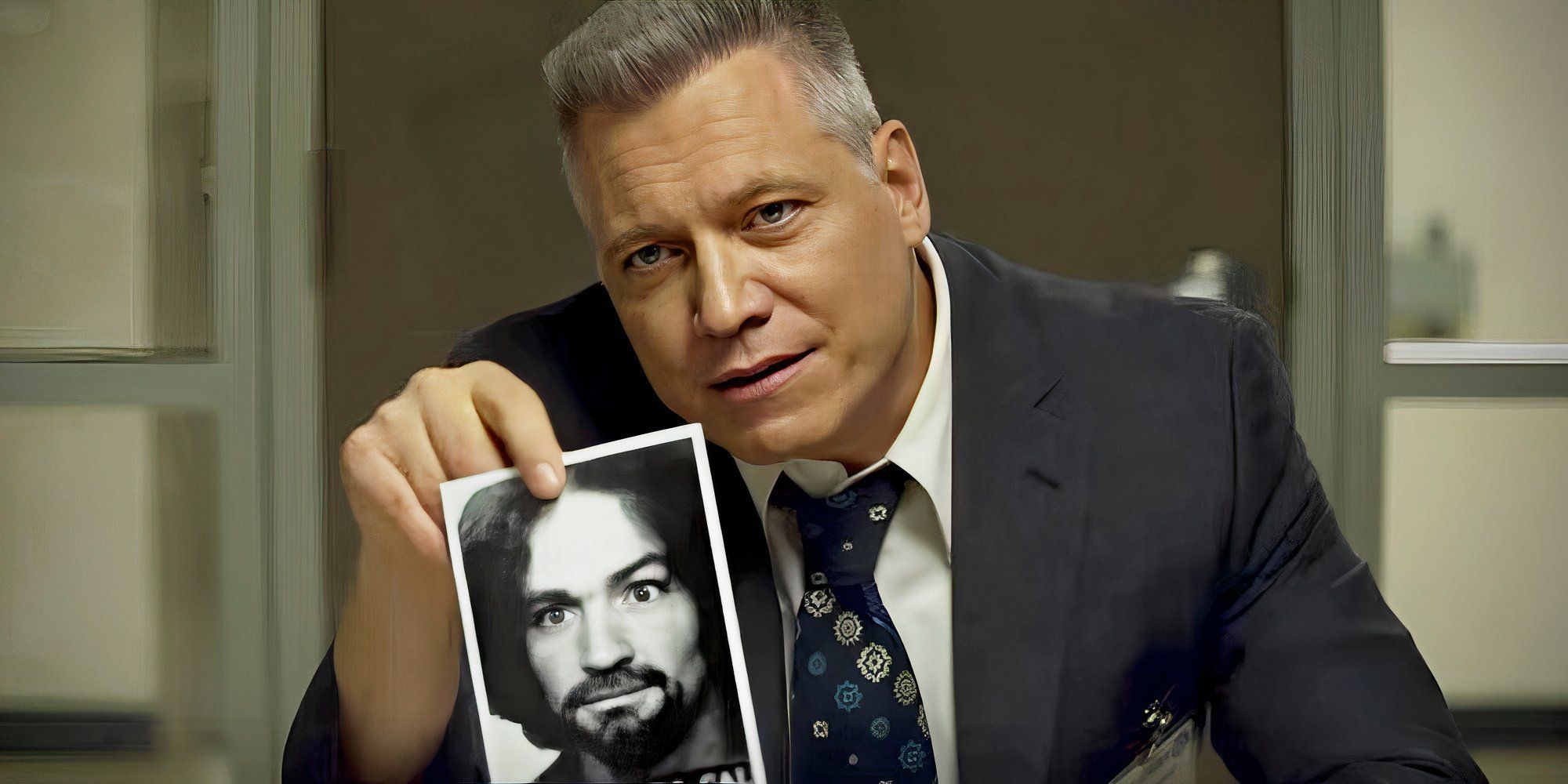 Bill Tench holding a picture of Charles Manson in Mindhunter