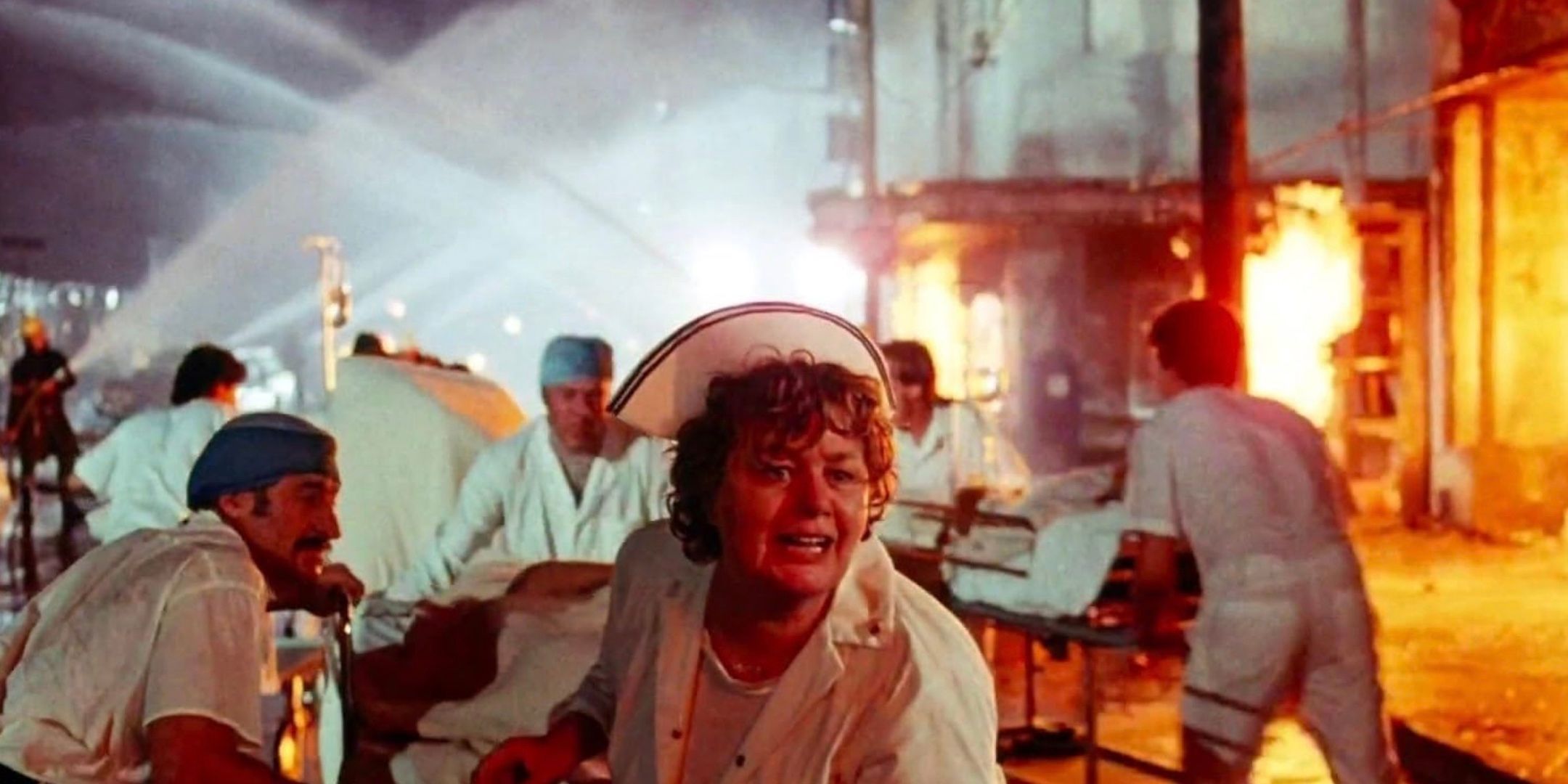 A group of people panic in the streets of a city that's engulfed in flames. 