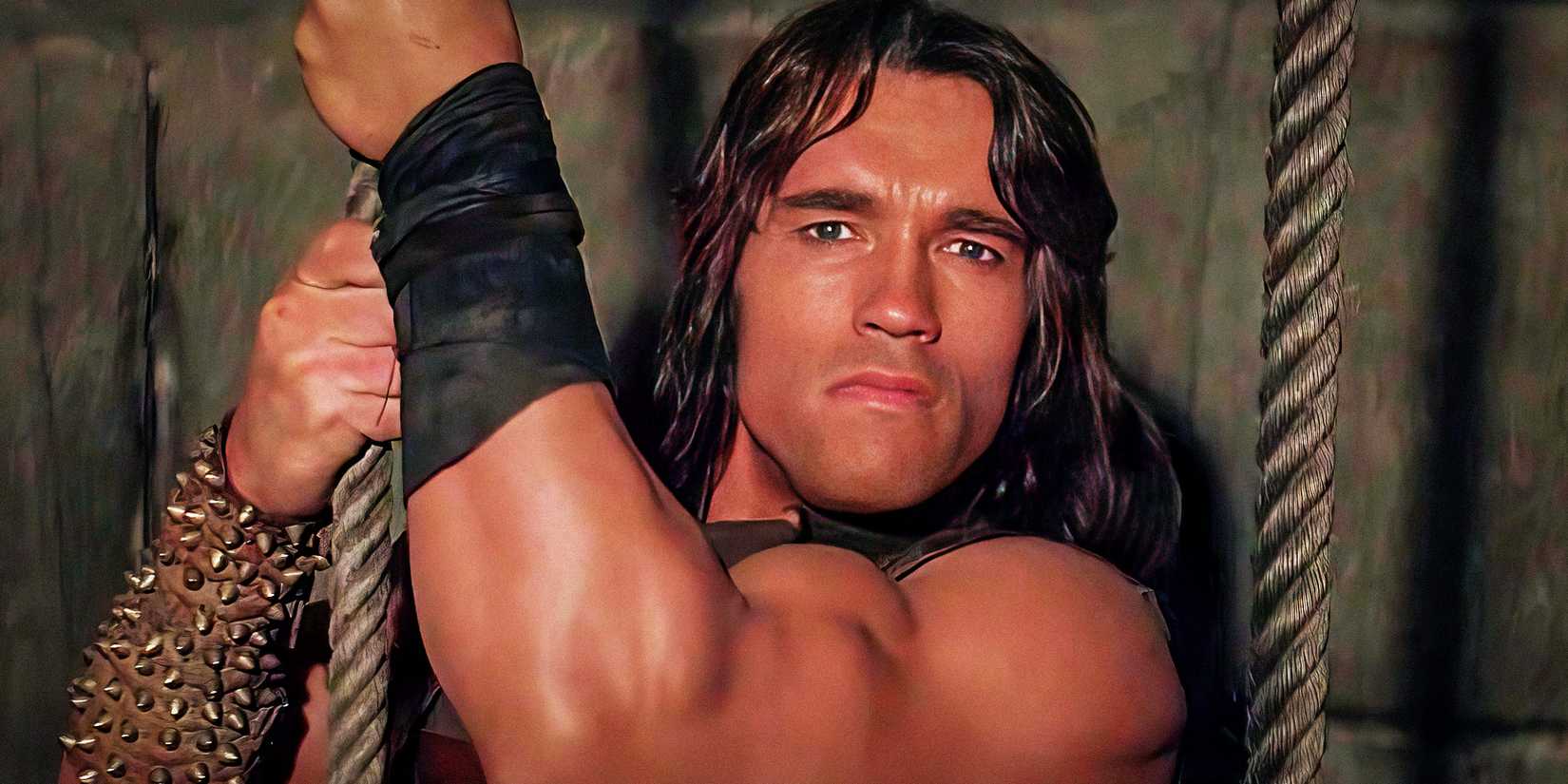 Arnold Schwarzenegger holding onto a rope as Conan in Conan the Barbarian