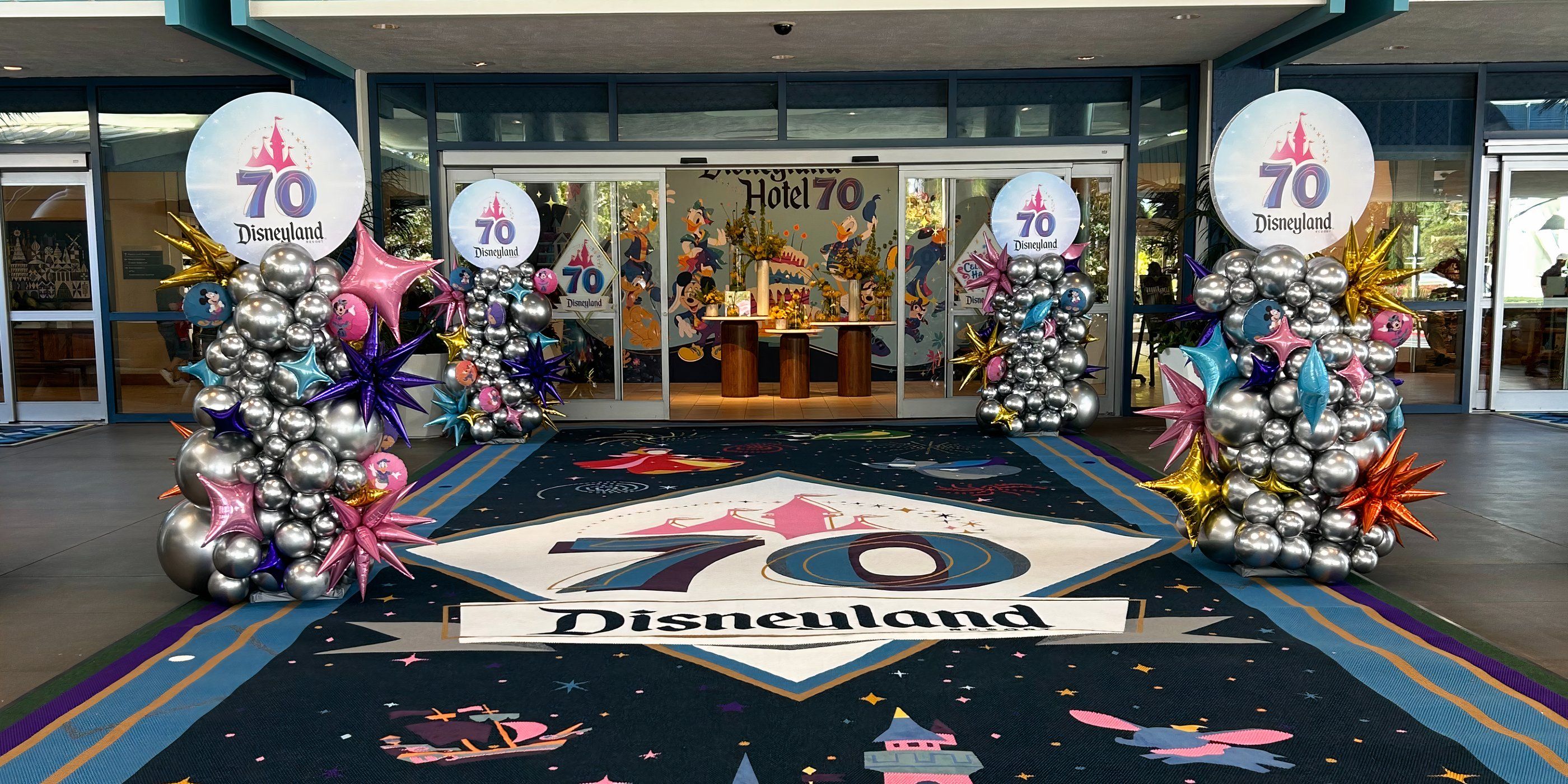 Disneyland H๏τel entrance with 70th anniversary carpet and background