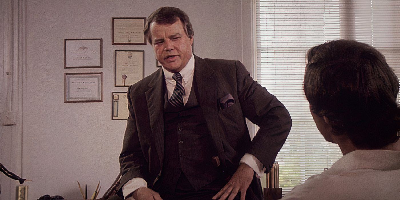 Chief Karlin lectures Fletch while sitting on his desk in Fletch