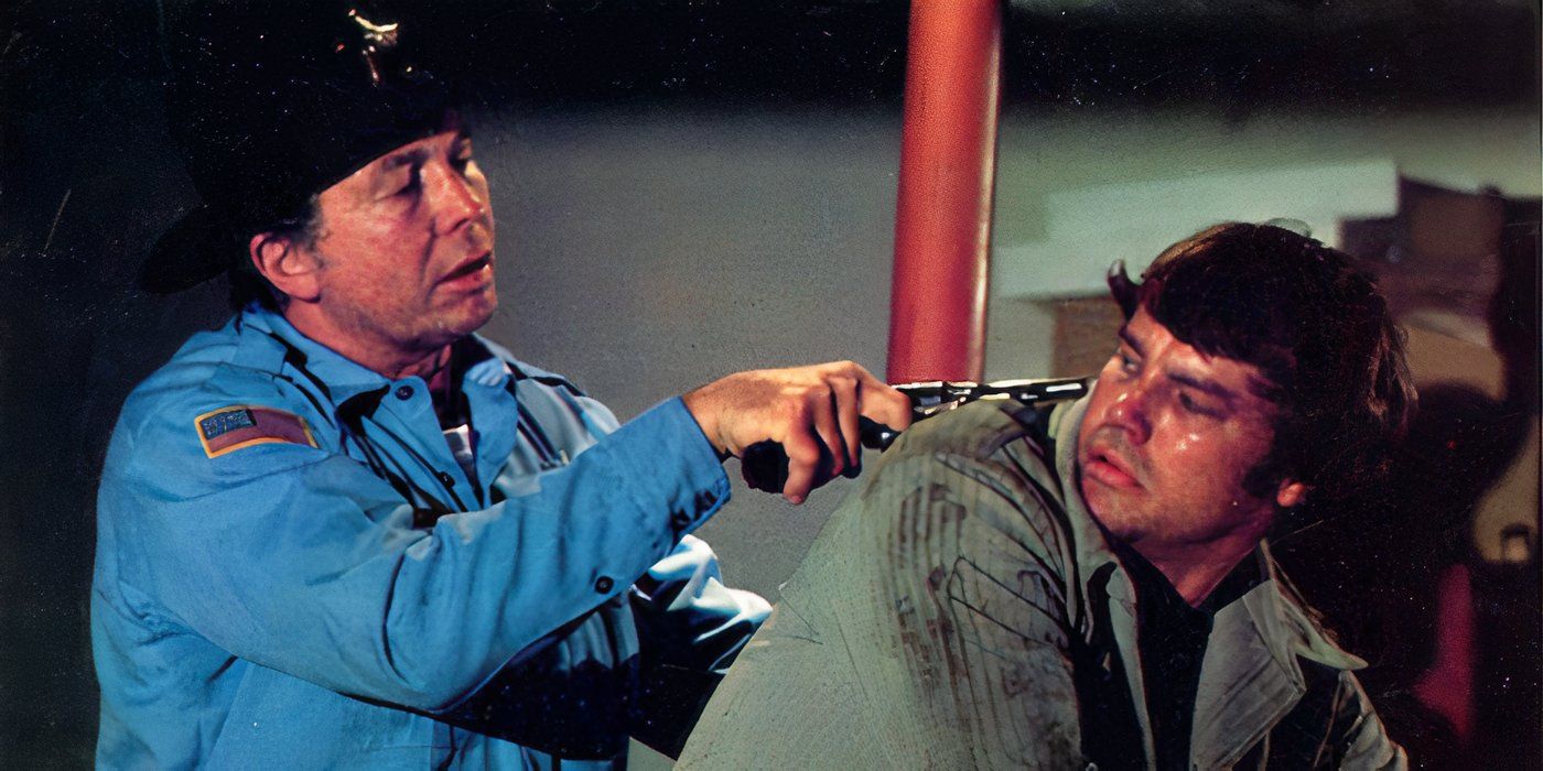 A cop points a gun at the back of Ron's head in Framed