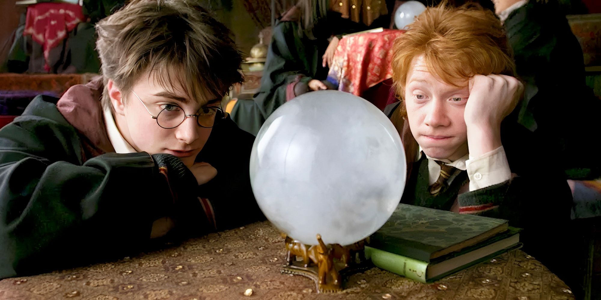 Daniel Radcliffe as Harry Potter and Rupert Grint as Ron Weasley looking at a crystal ball in Harry Potter.