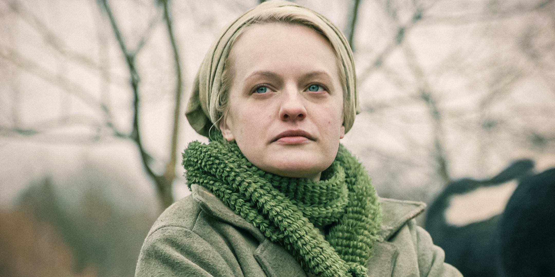 June is bundled up in a green bandana, jacket, and scarf in The Handmaid's Tale.