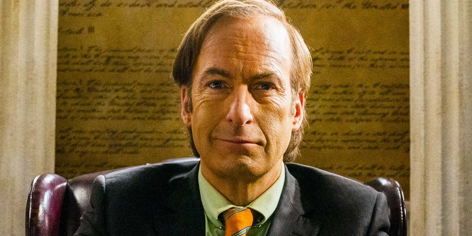 Jimmy McGill/Saul Goodman (Bob Odenkirk) smiling while sitting in his office in Better Call Saul season 6