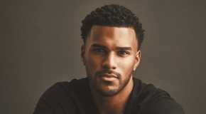 Jeremiah Brown from Love Island USA smiling in front of a black backdrop.