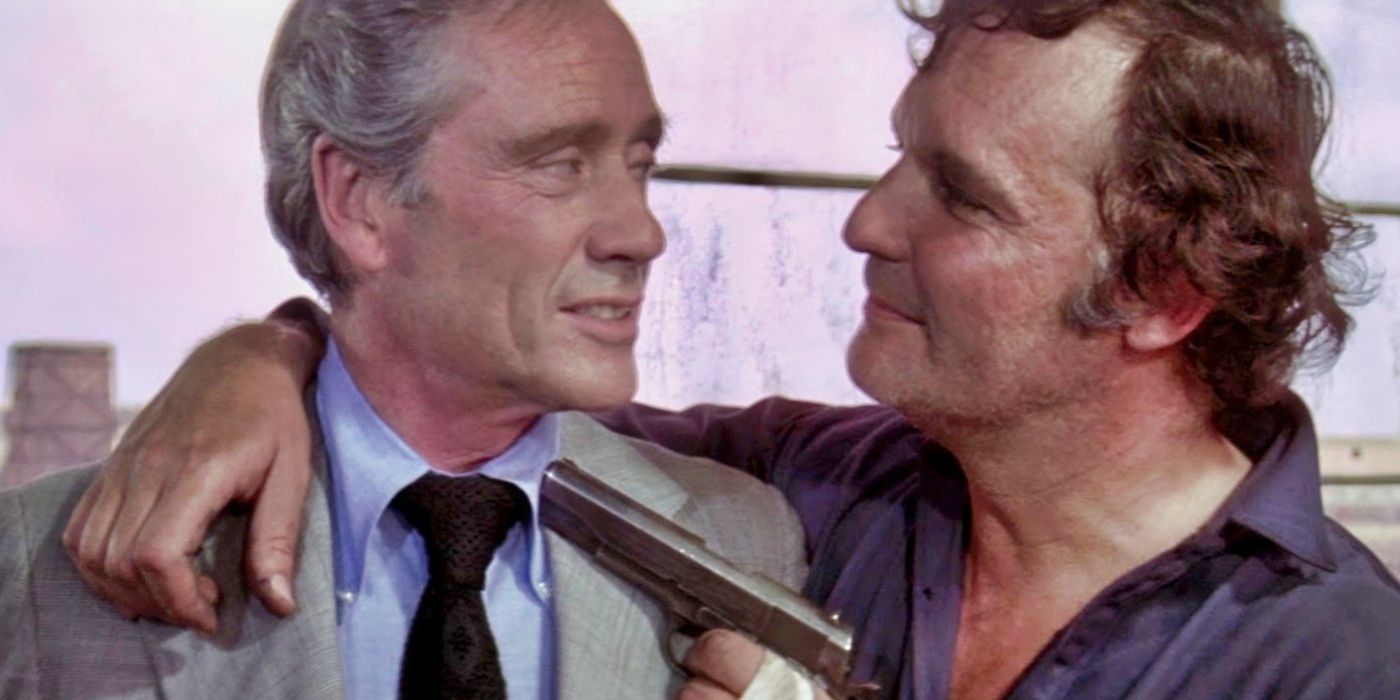 John Vernon pointing a gun at Mel Ferrer in Brannigan