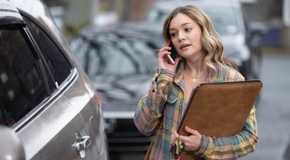 Lola on her phone and holding a large file in Sullivan's Crossing