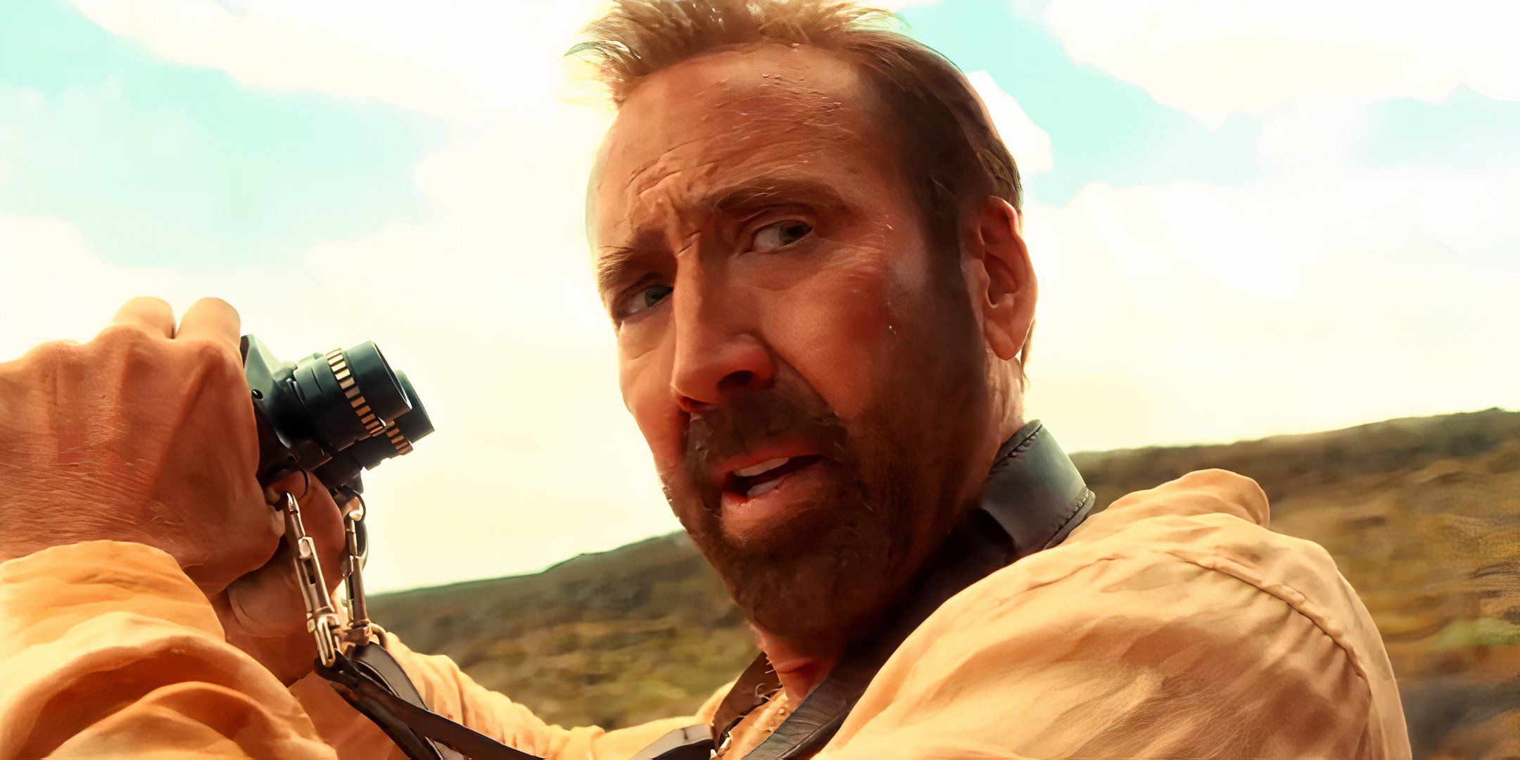 Nicolas Cage looking worried while holding binoculars in The Surfer