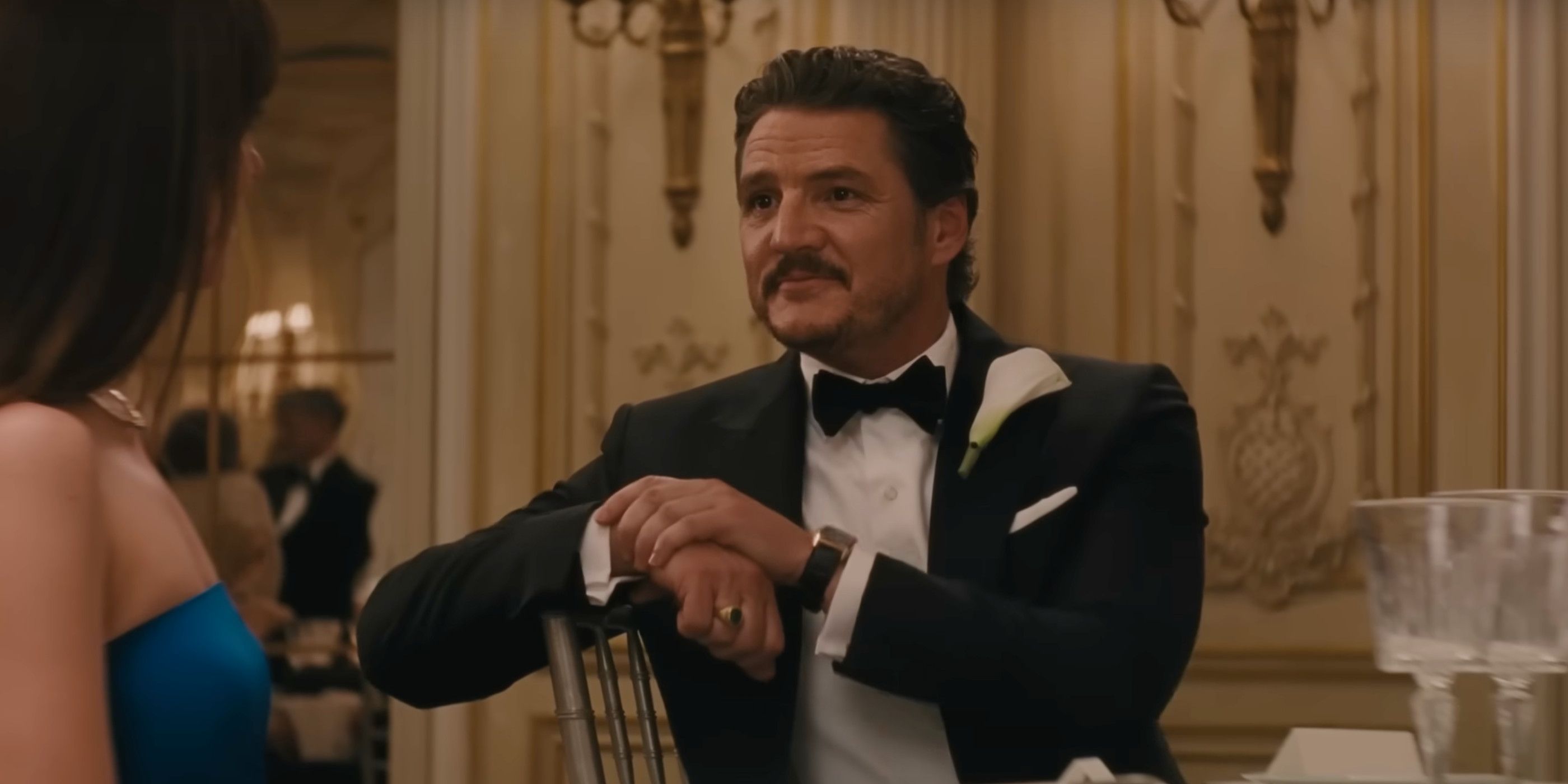 Pedro Pascal Materialists sitting in a suit at a dinner table 