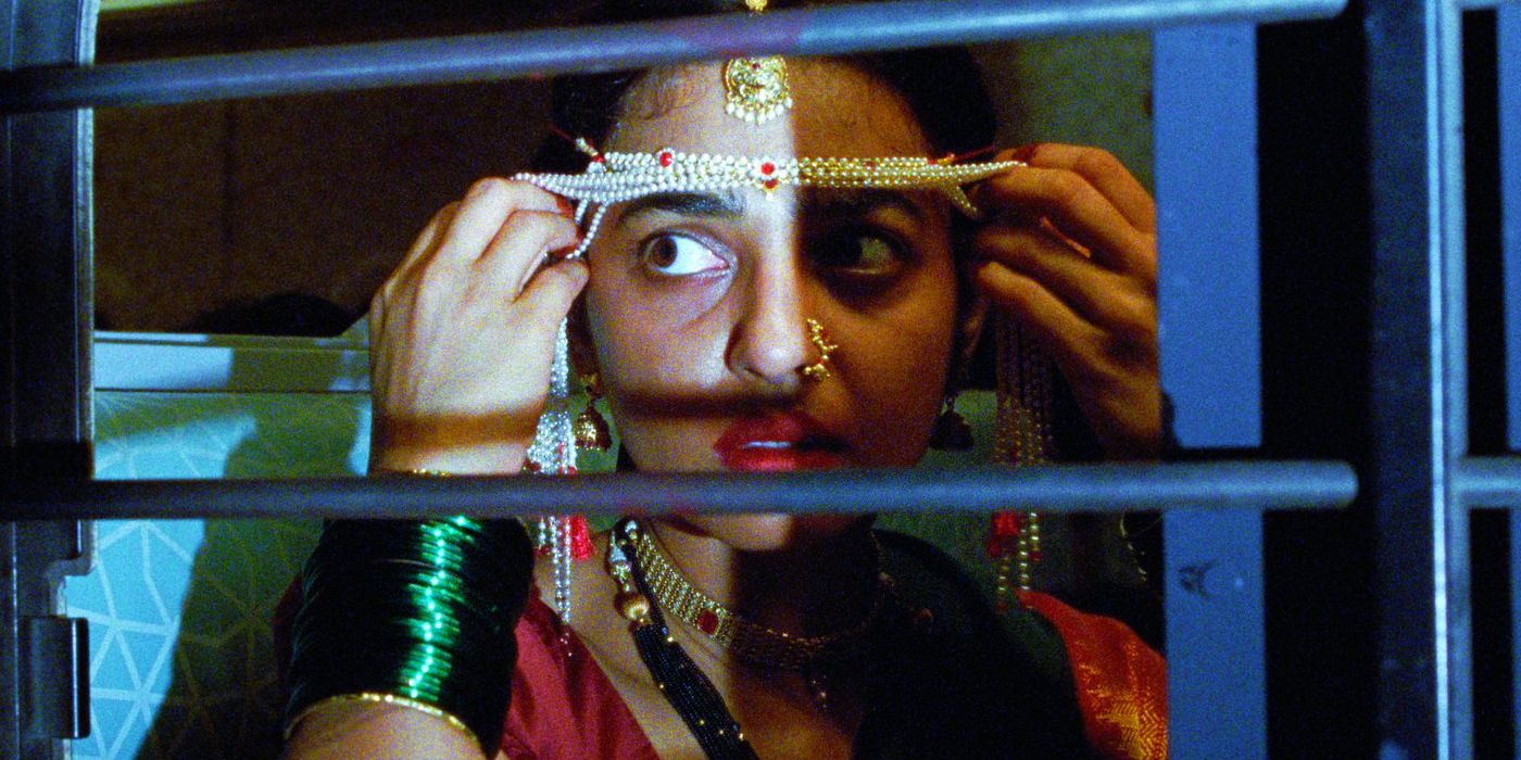 Radhika Apte as Uma peering through a beaded veil out a train window in Sister Midnight