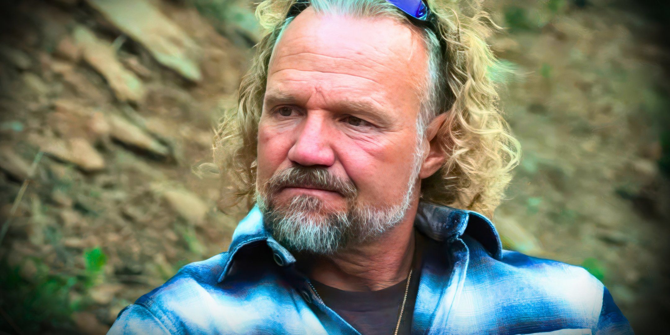 Sister Wives star Kody brown in a blue plaid shirt looking anguished in still with outdoor background