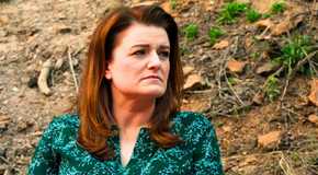 sister wives star robyn brown in a green blouse looking to the side with leaves in the background