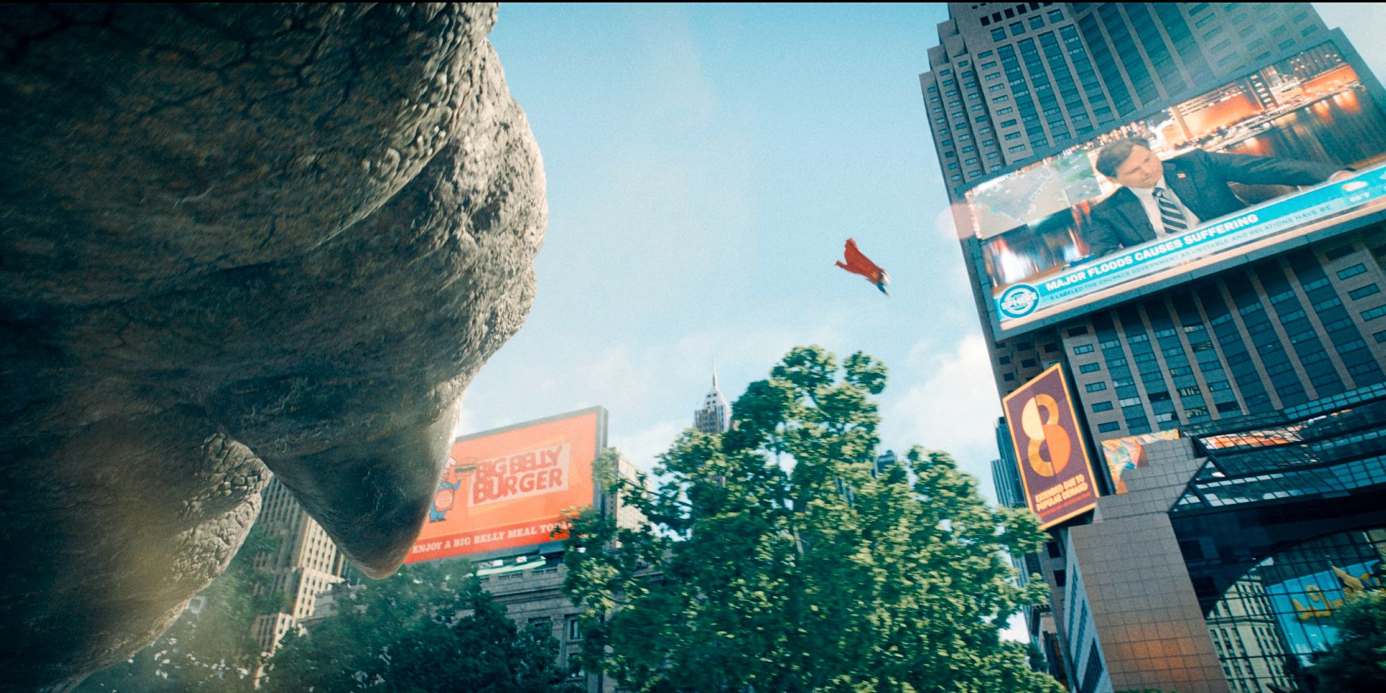 Superman flies to save a pedestrian from a monster's foot in Metropolis
