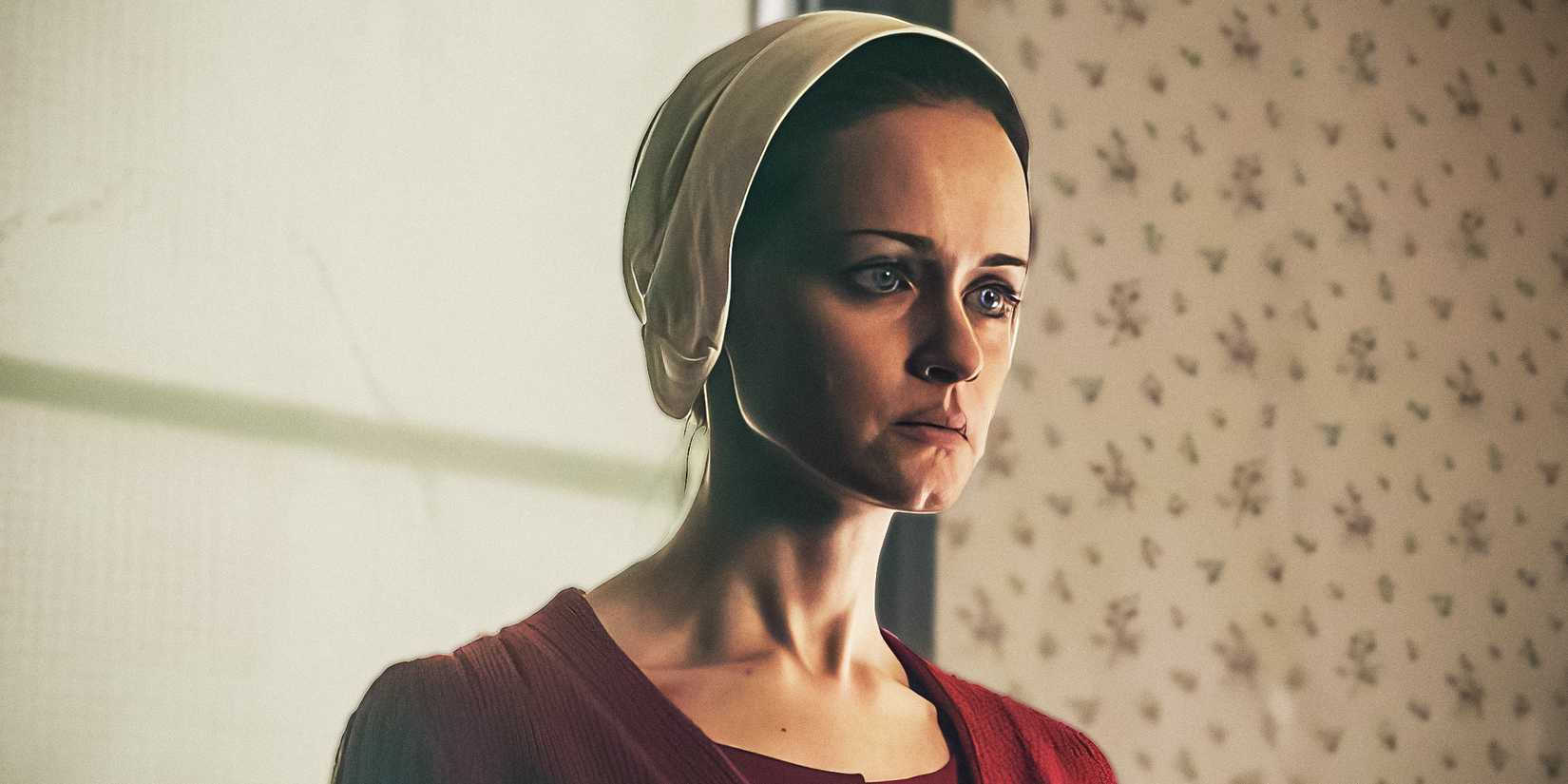 Alexis Bledel's Emily looks to the side in The Handmaid's Tale while wearing her red robe and bonnet.