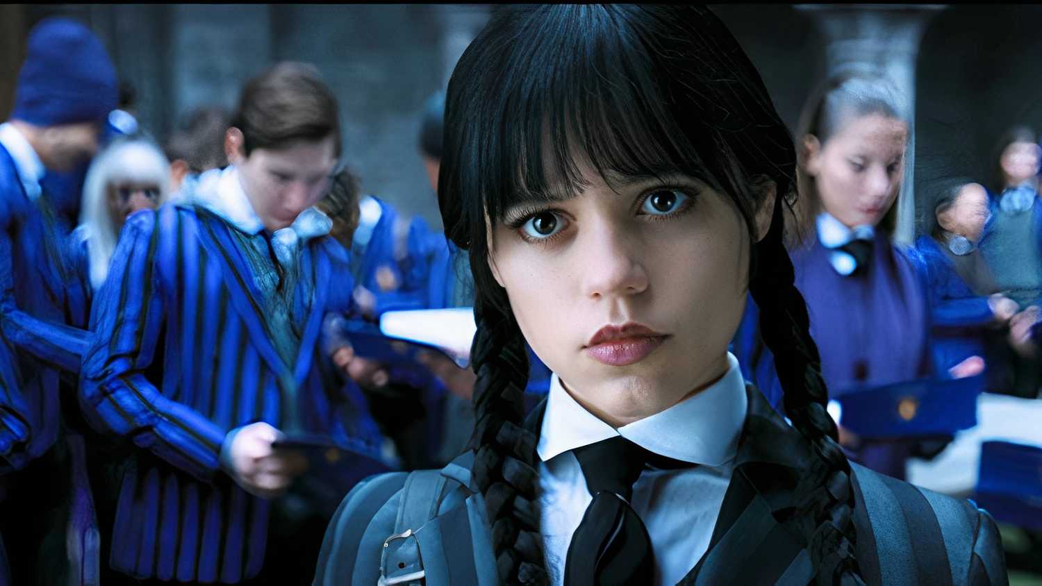 Jenna Ortega as Wednesday Addams, standing in the foreground with a group of students in blue striped uniforms in the background