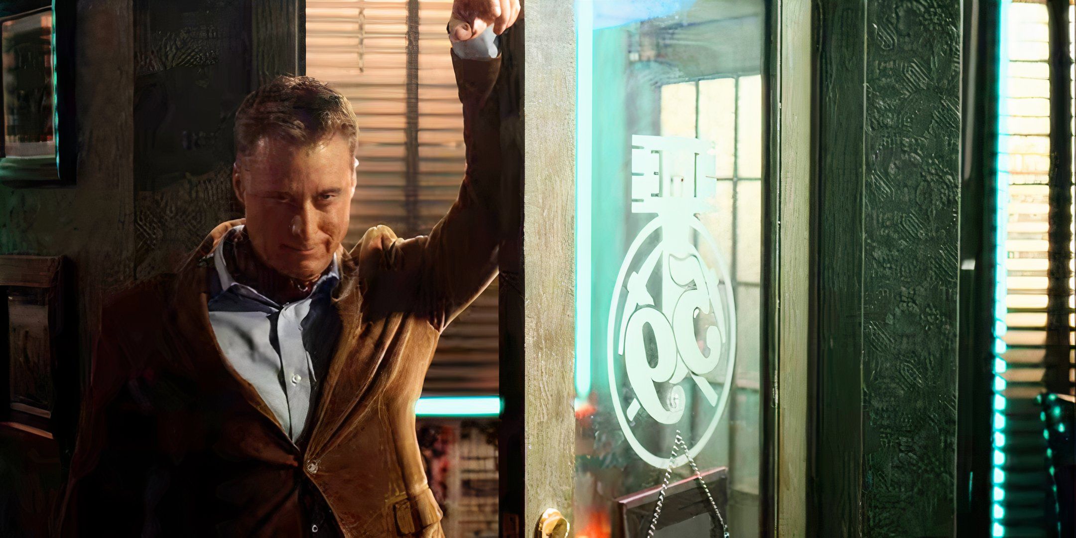 Harry in a brown coat leaning suggestively against a door 