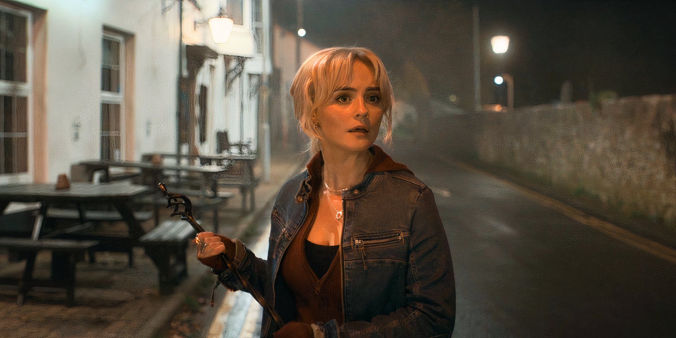 Ruby Sunday holding an iron rod outside of a pub at night