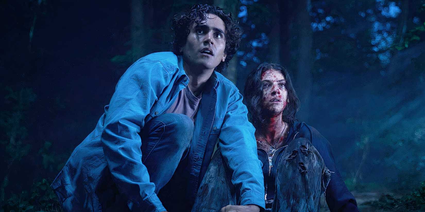 Michael Cimino and Ella Rubin sitting outside in the woods with nervous expressions in Until Dawn