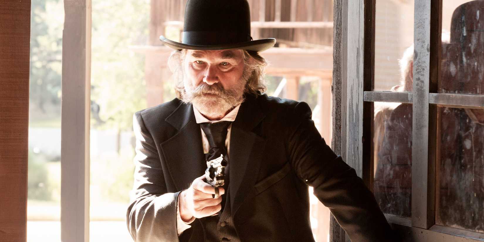Kurt Russell enters a building pointing a gun in a scene from Bone Tomahawk