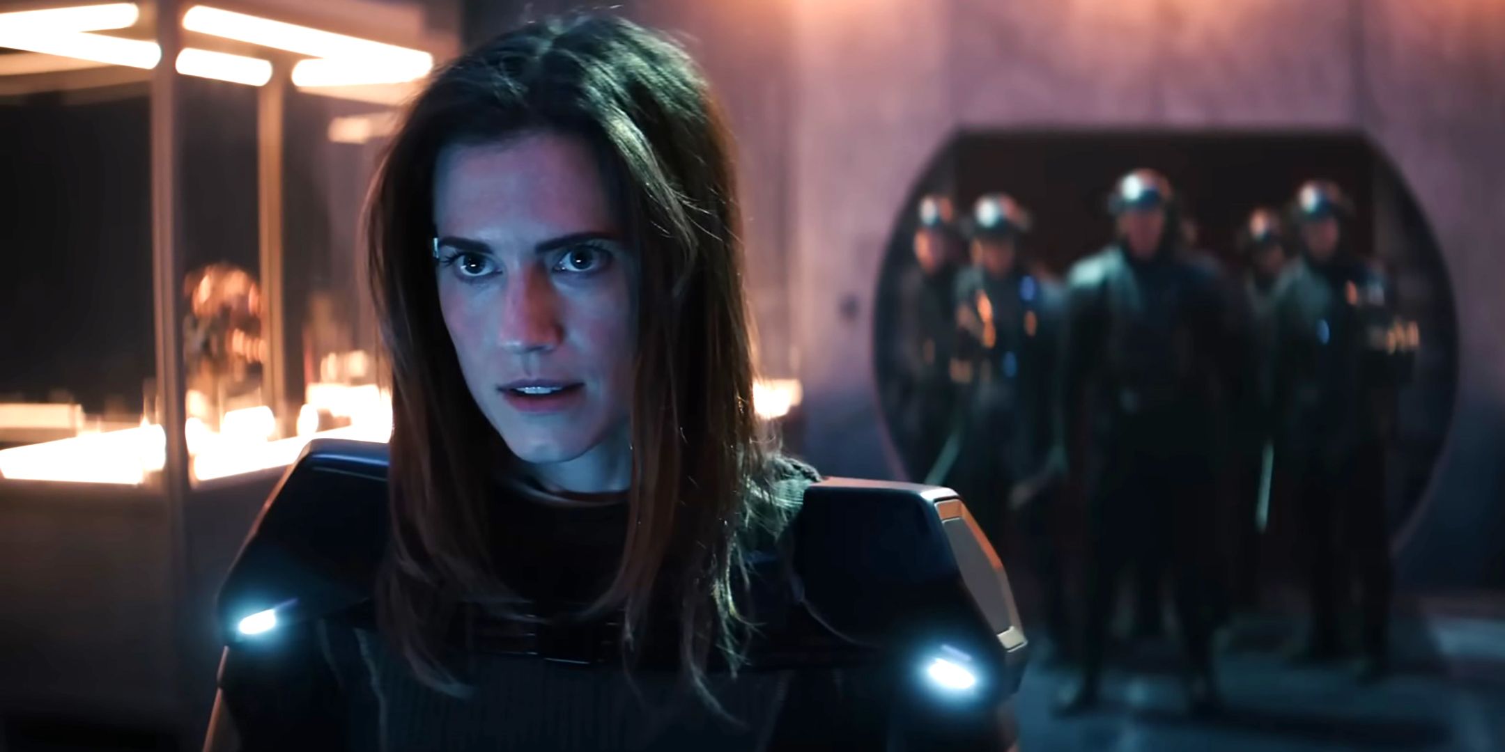 Alison Williams' Gemma looking intense in a fight suit with soldiers behind her in M3GAN 2.0