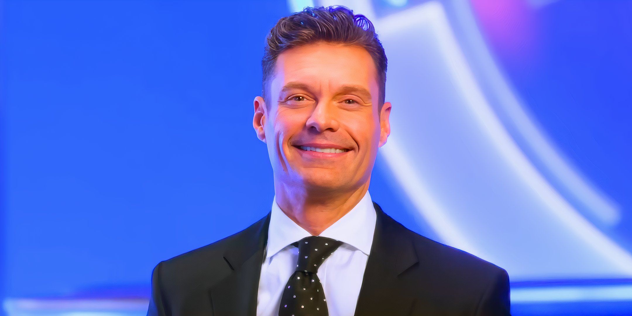 american idol star ryan seacrest smilng in a suit with a blue white and purple background