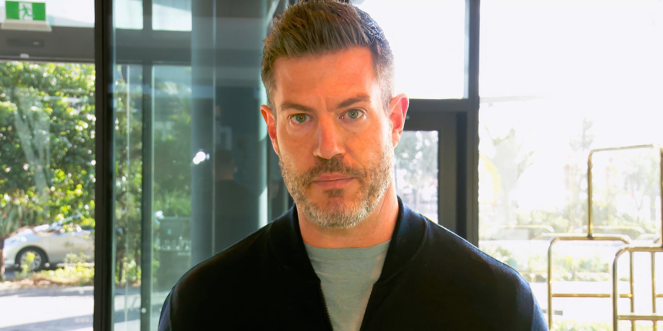 bachelor in paradise star jesse palmer in a black jacket looking serious in a house