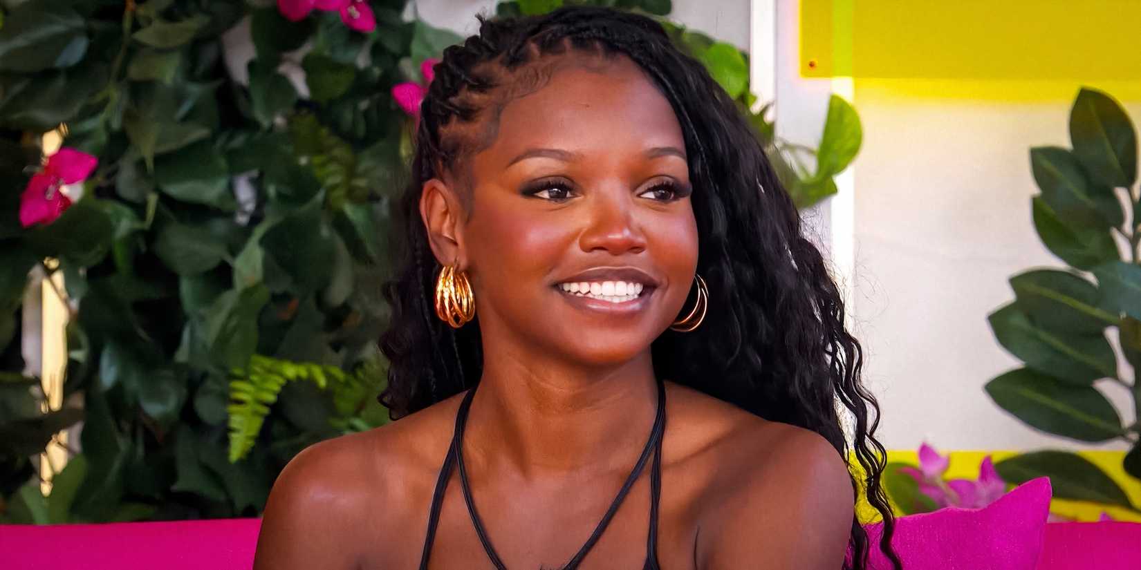 Chelley Bissainthe from Love Island USA Season 7 smiling on a pink couch in front of a plant