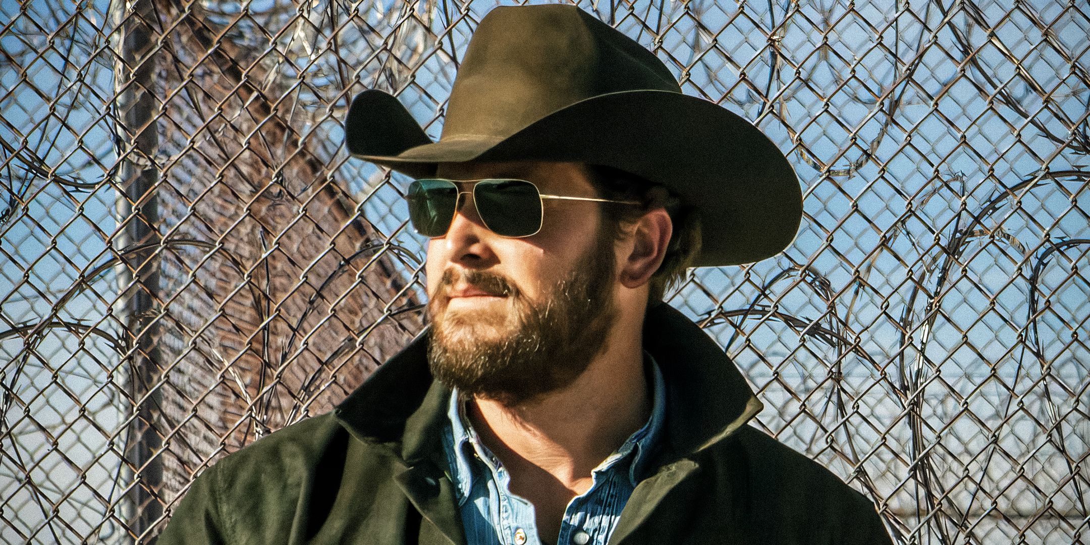 Cole Hauser as Rip Wheeler wearing sunglasses and cowboy hat looking off into the distance in Yellowstone