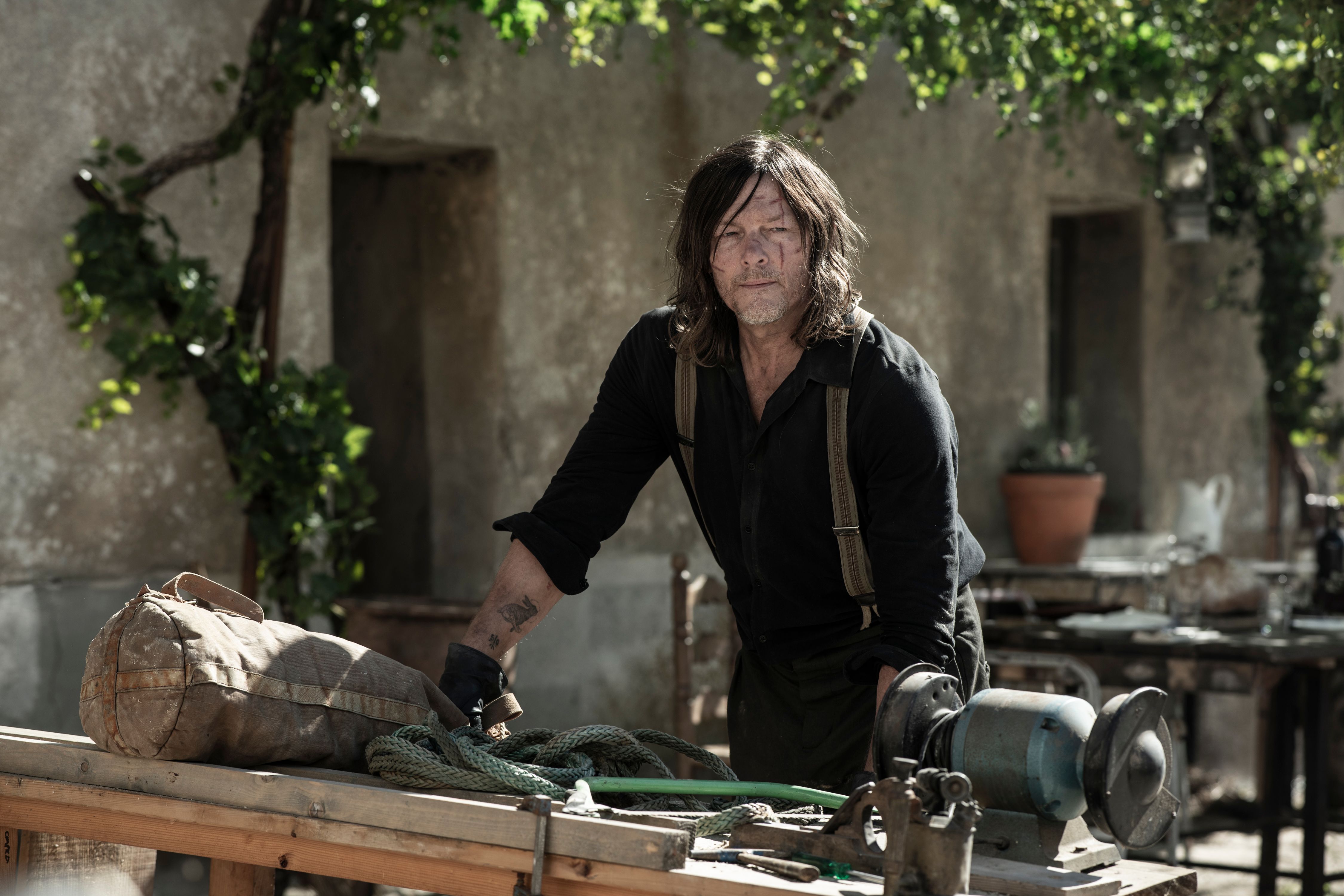 Norman Reedus as Daryl leaning over a table in The Walking Dead: Daryl Dixon season 3