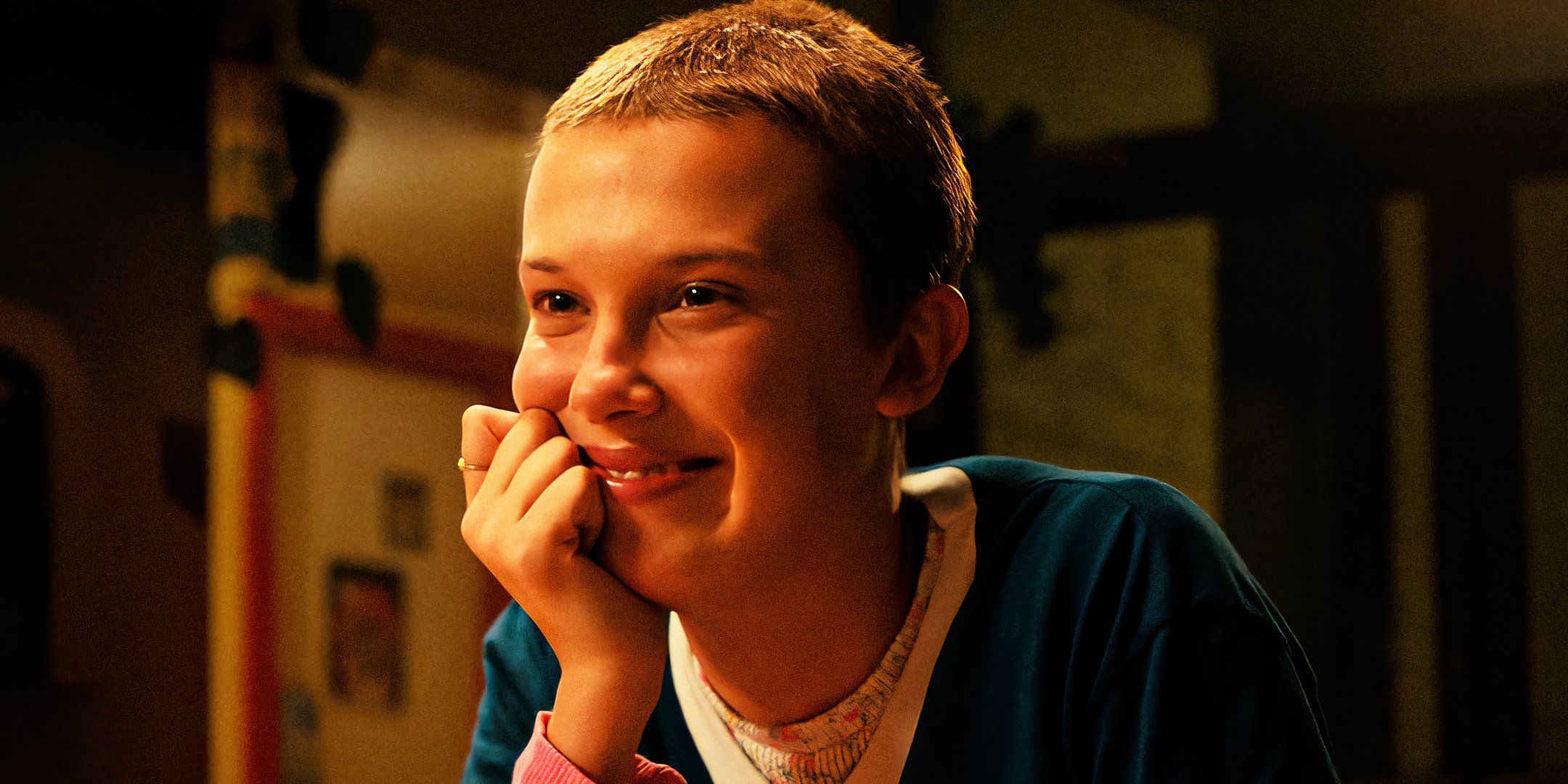 Eleven smiling with a shaved head in Stranger Things