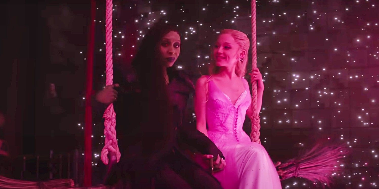 Elphaba and Glinda bathed in a pink light sitting on a broom in Wicked For Good