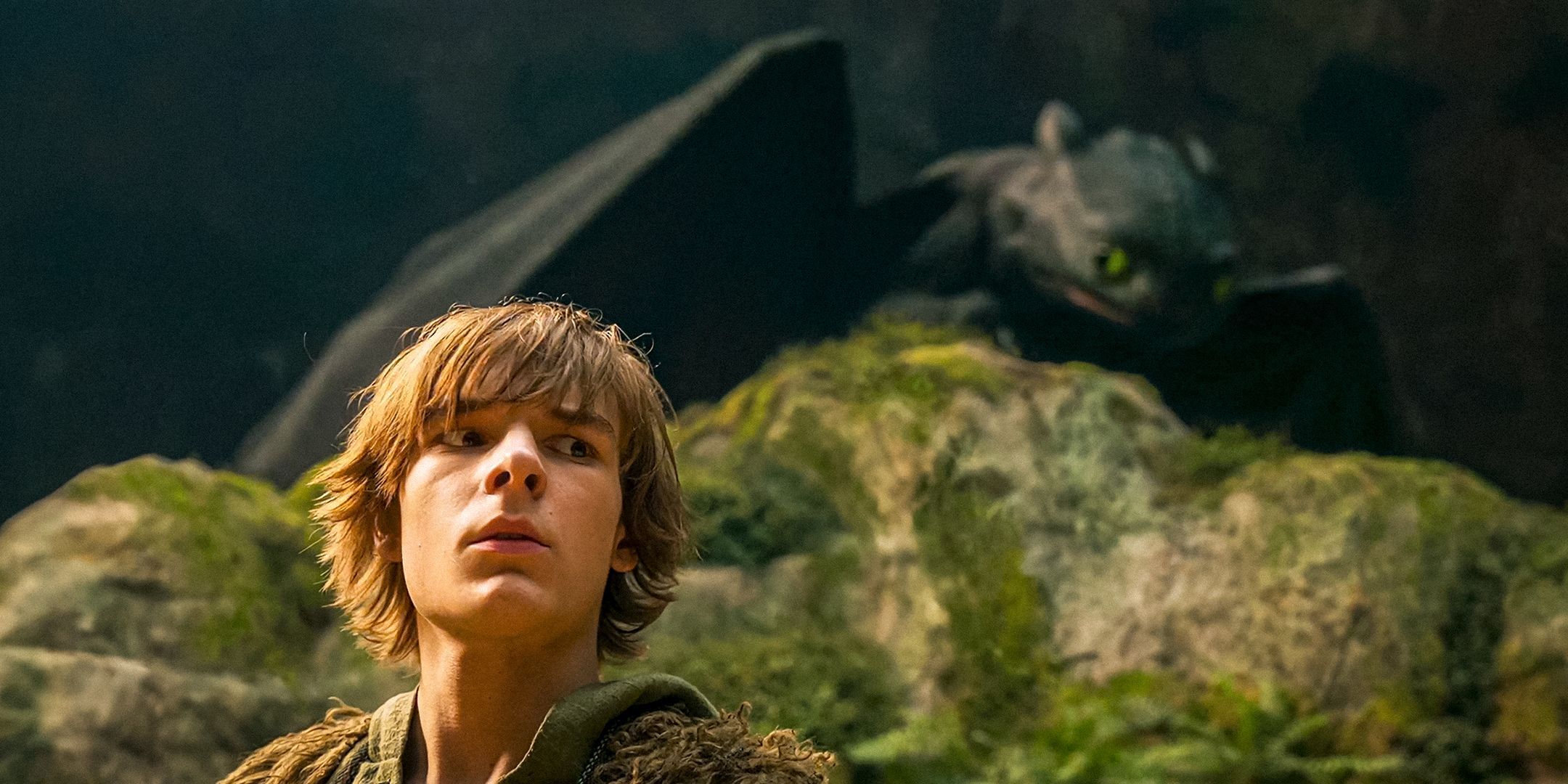 Mason Thames as Hiccup hiding from Toothless behind a rock in How to Train Your Dragon 2025