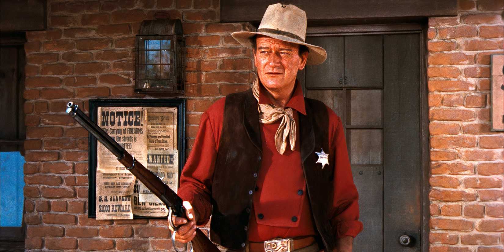 John Wayne holds up a rifle while standing in front of the Sheriff's Office in Rio Bravo