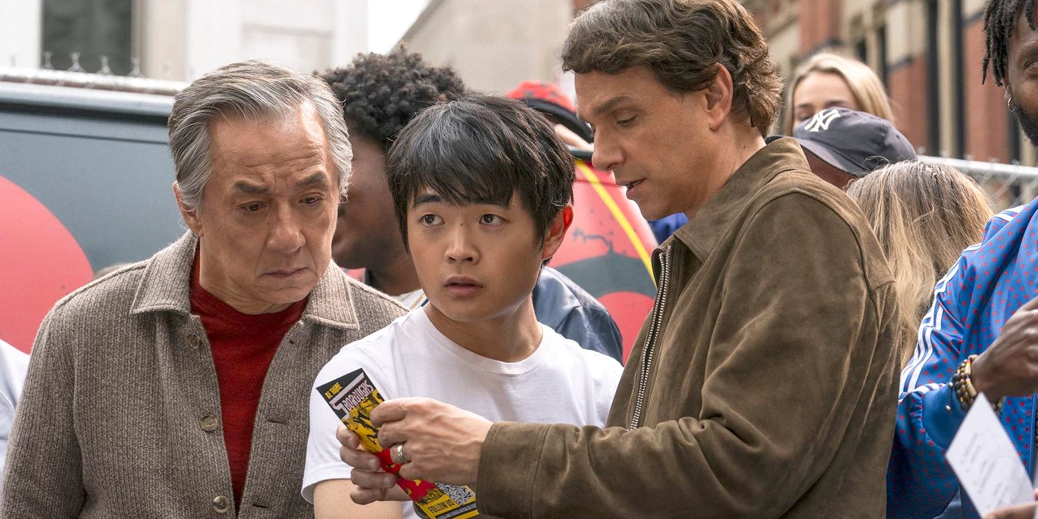 Mr. Han (Jackie Chan), Li Fong (Ben Wang), and Daniel LaRusso (Ralph Macchio) on the street looking at a flyer in Karate Kid- Legends