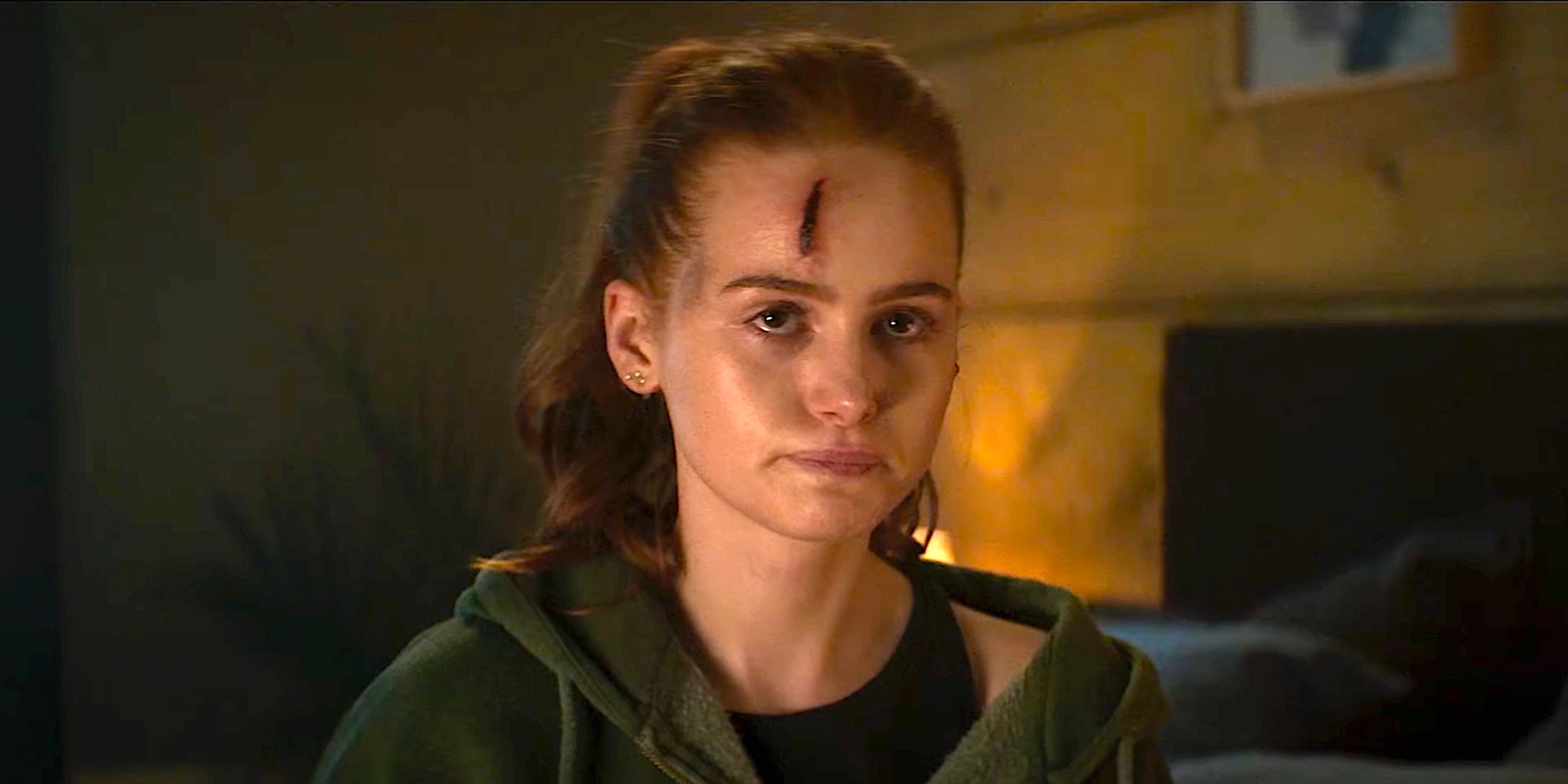 Madelaine Petsch's Maya looks worried sitting on a couch with a head wound in The Strangers Chapter 2