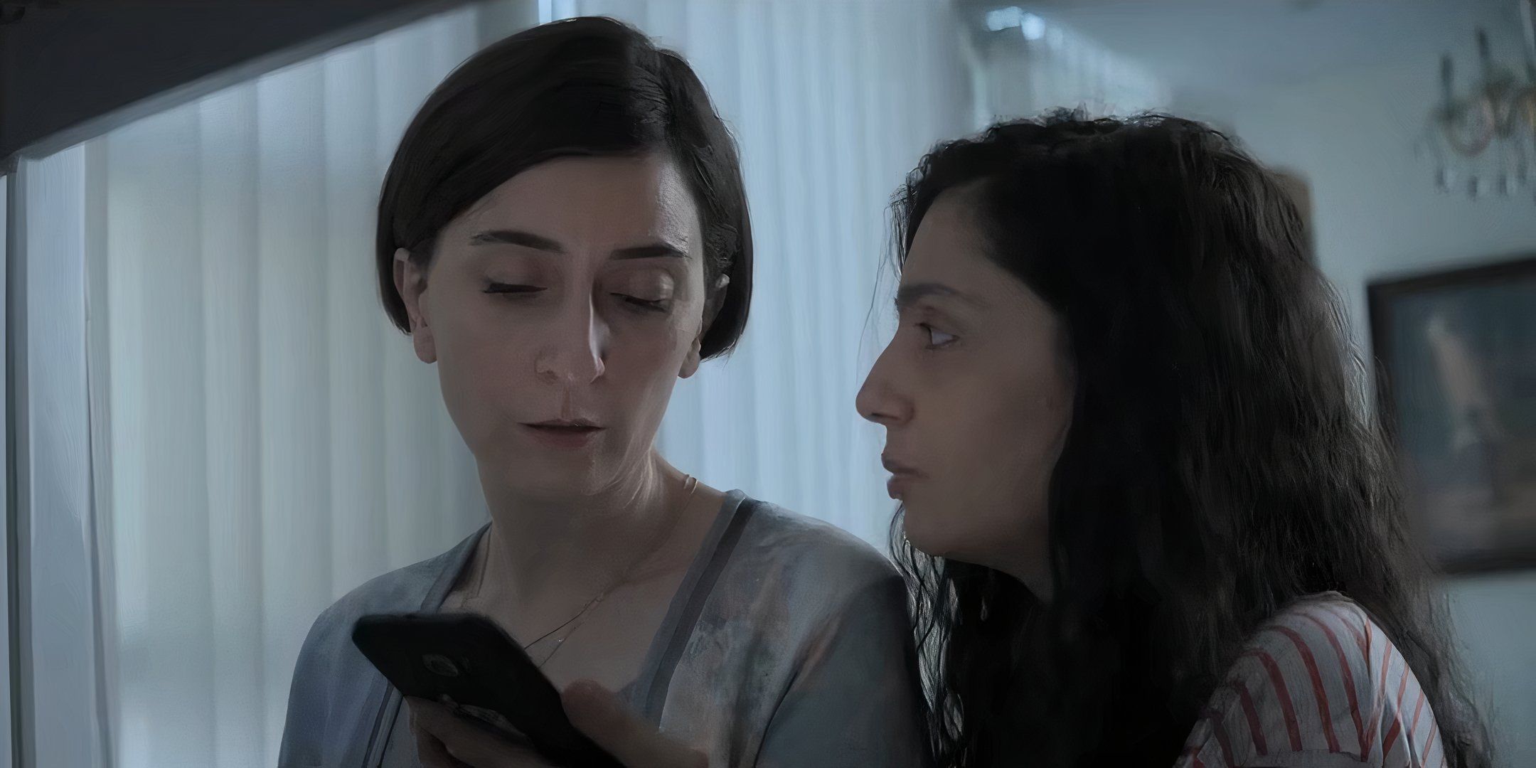 Mahsa Rostami as Rezvan and Setareh Maleki as Sana looking at a phone in The Seed of the Sacred Fig-1