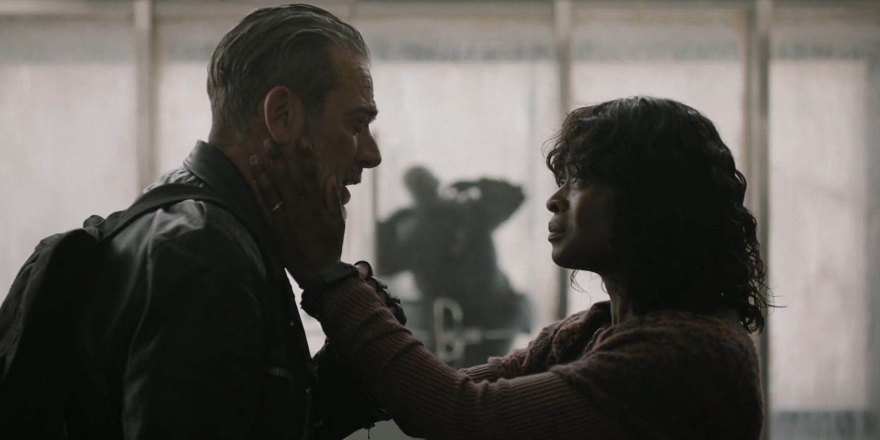 Negan (Jeffrey Dean Morgan) and Annie (Medina Senghore) embracing while a zombie hits the glass behind them in The Walking Dead: Dead City season 2