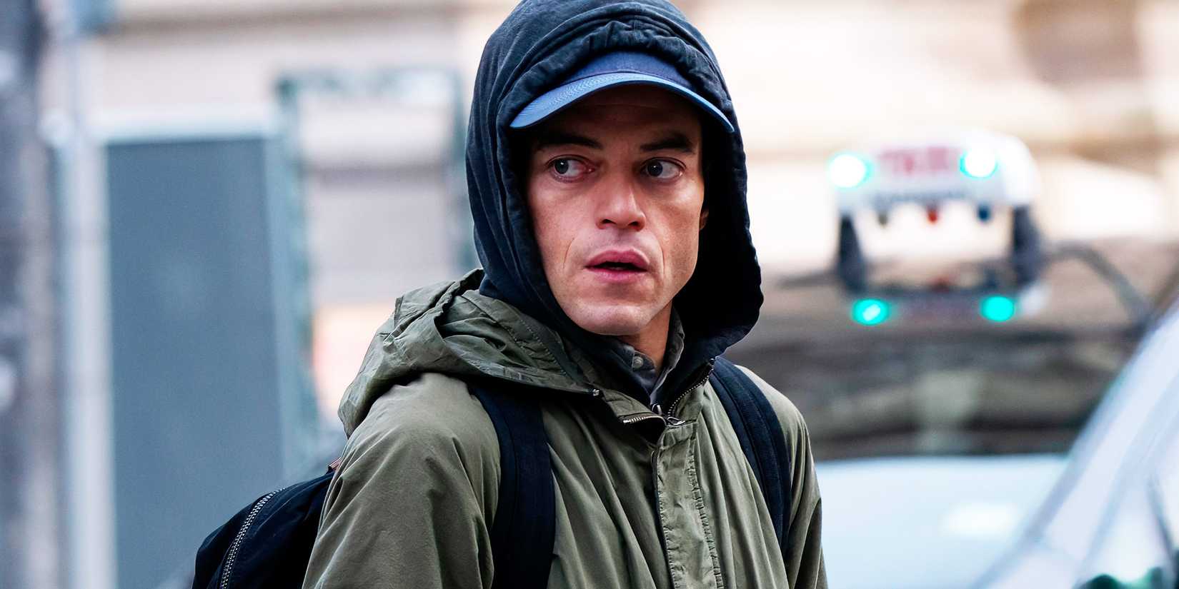 Rami Malek looking nervous while wearing a hoodie in The Amateur
