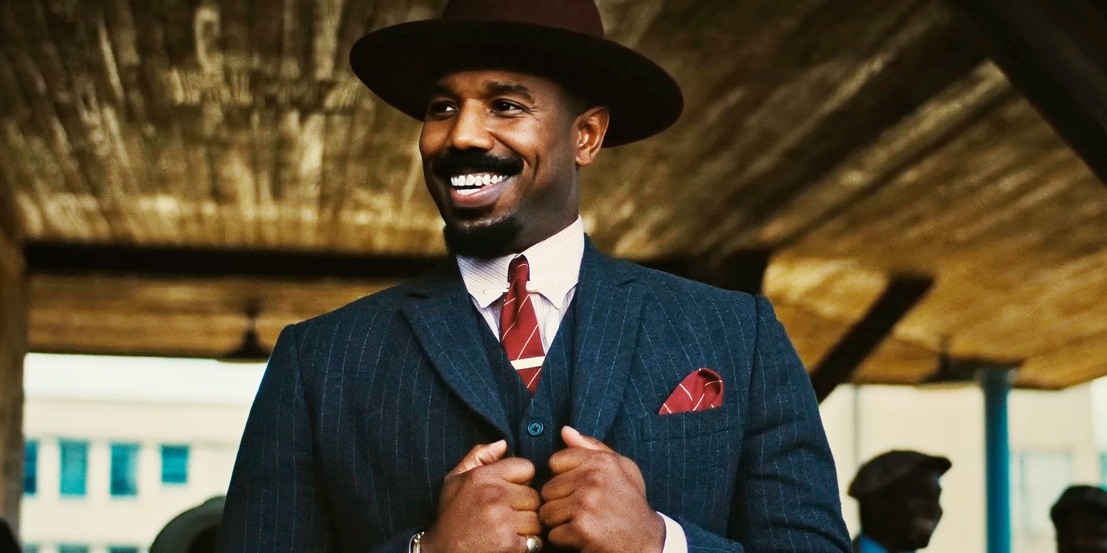 Michael B. Jordan tersenyum dalam setelan jas di Sinners