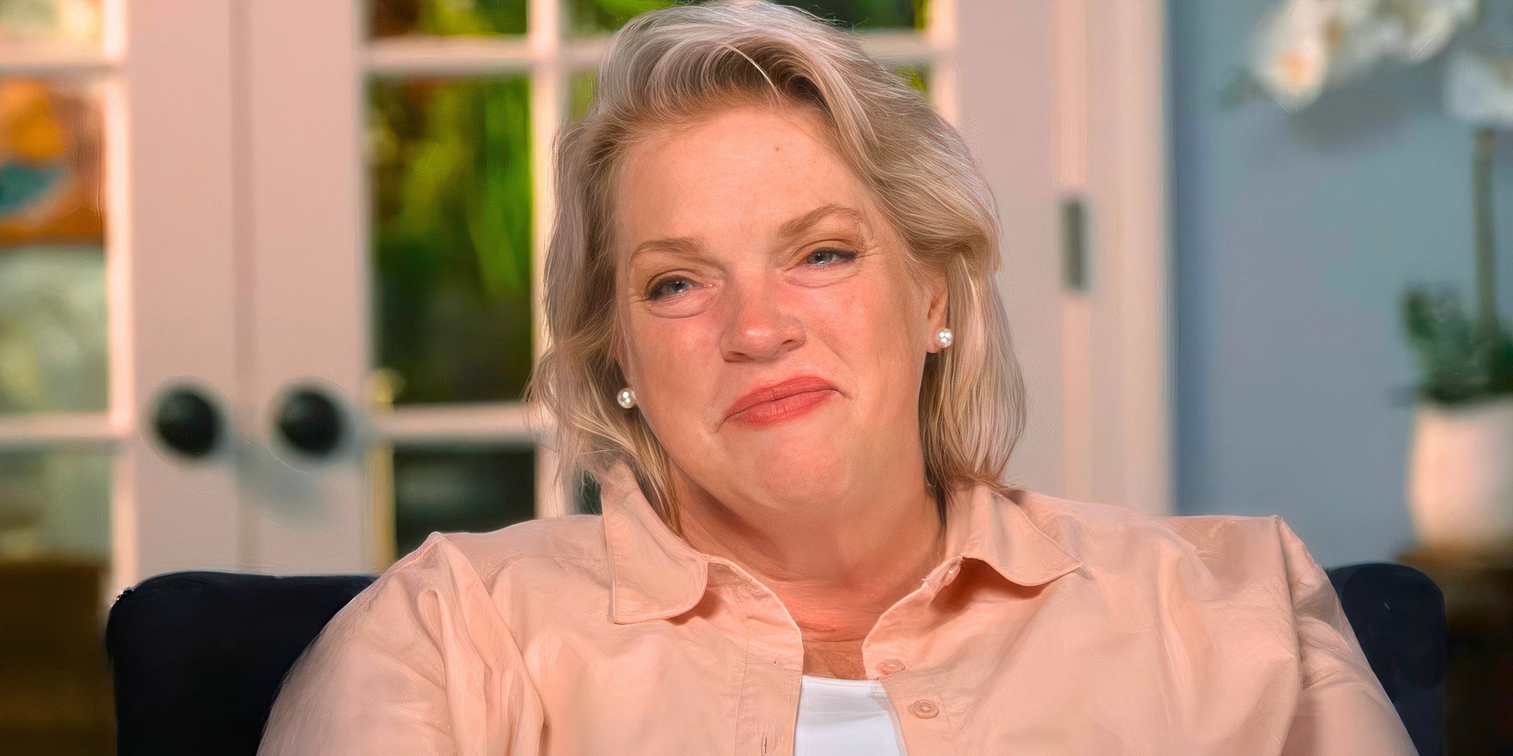 sister wives star janelle brown in a pink shirt smiling in a living room