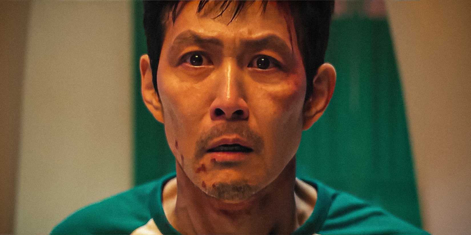 Lee Jung-jae as Gi-hun looking shocked and emotional with blood on his face in Squid Game