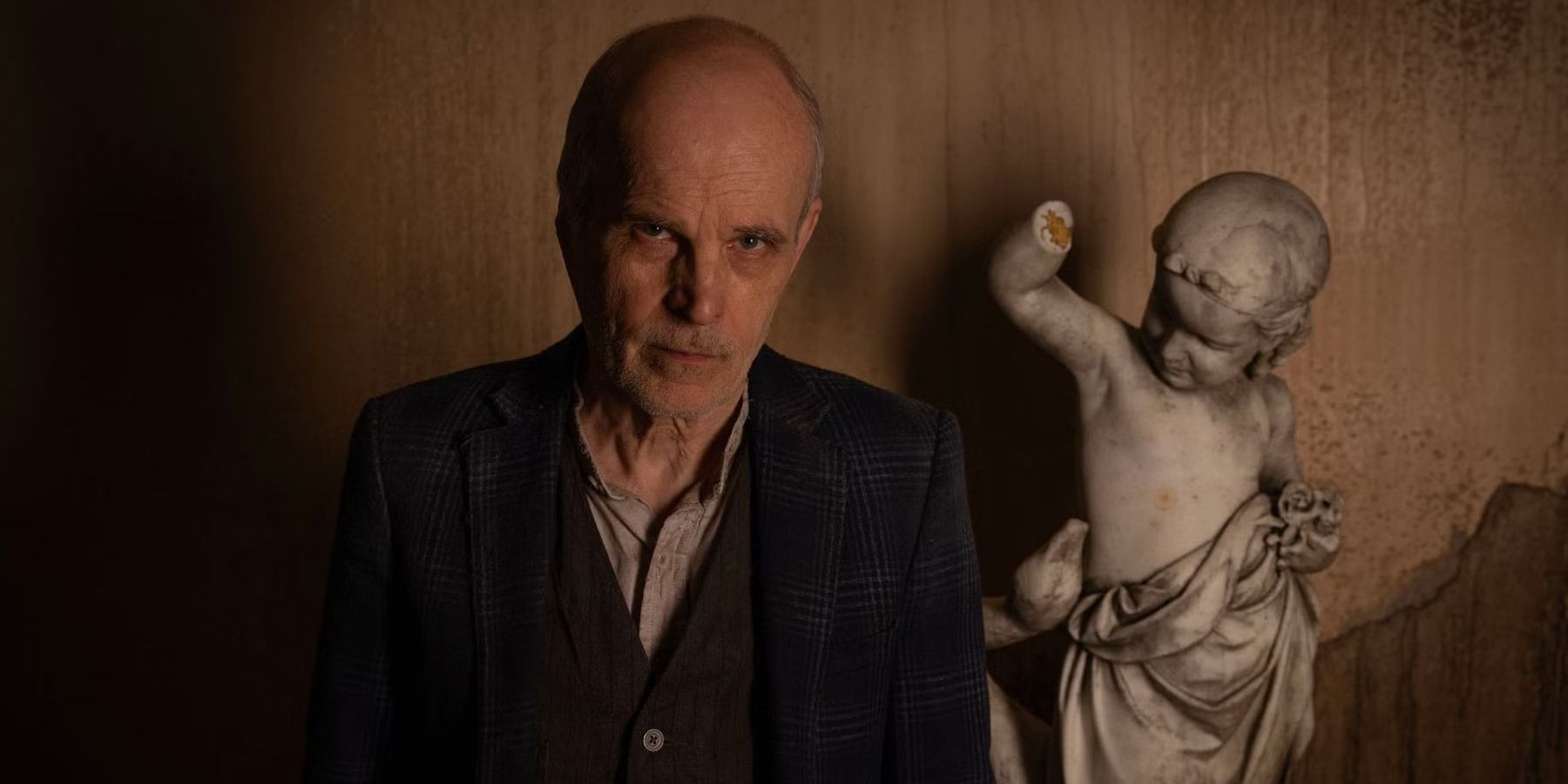 The Croat (Željko Ivanek) looking glum while standing next to a statue in The Walking Dead: Dead City season 2