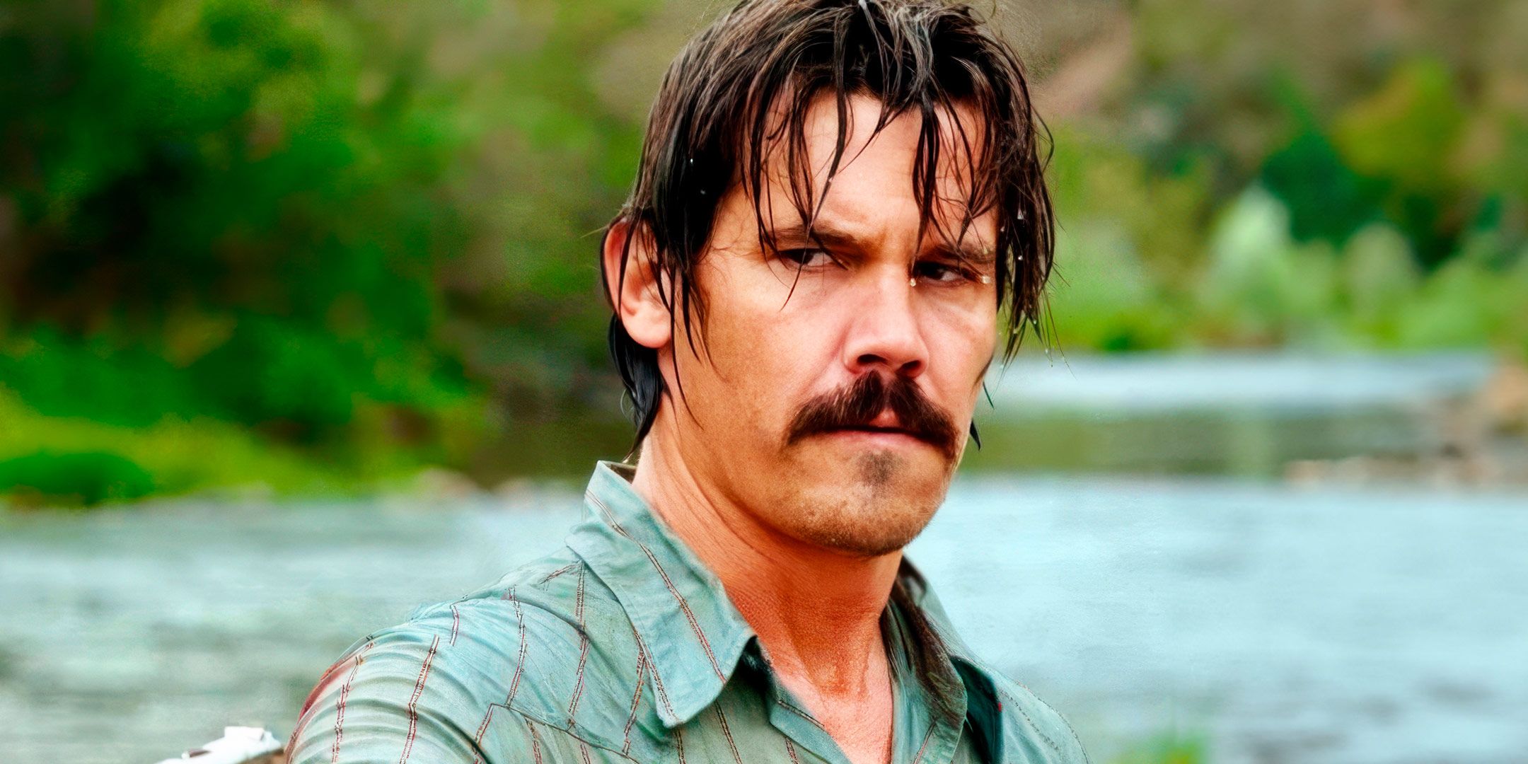 Josh Brolin peers warily while soaking wet in the river in a scene from No Country For Old Men