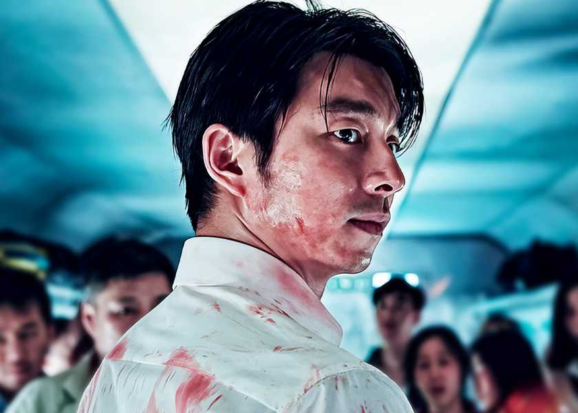 Seok-woo looks over his shoulder while standing in the aisle in Train to Busan