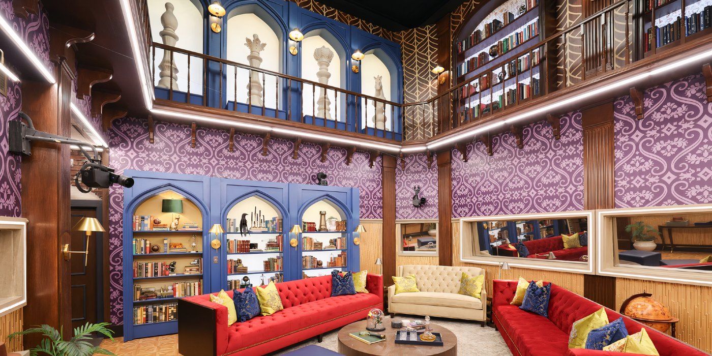 Big Brother 27's living room area with purple and blue lavish walls, two red couches, and a white love seat in the middle.